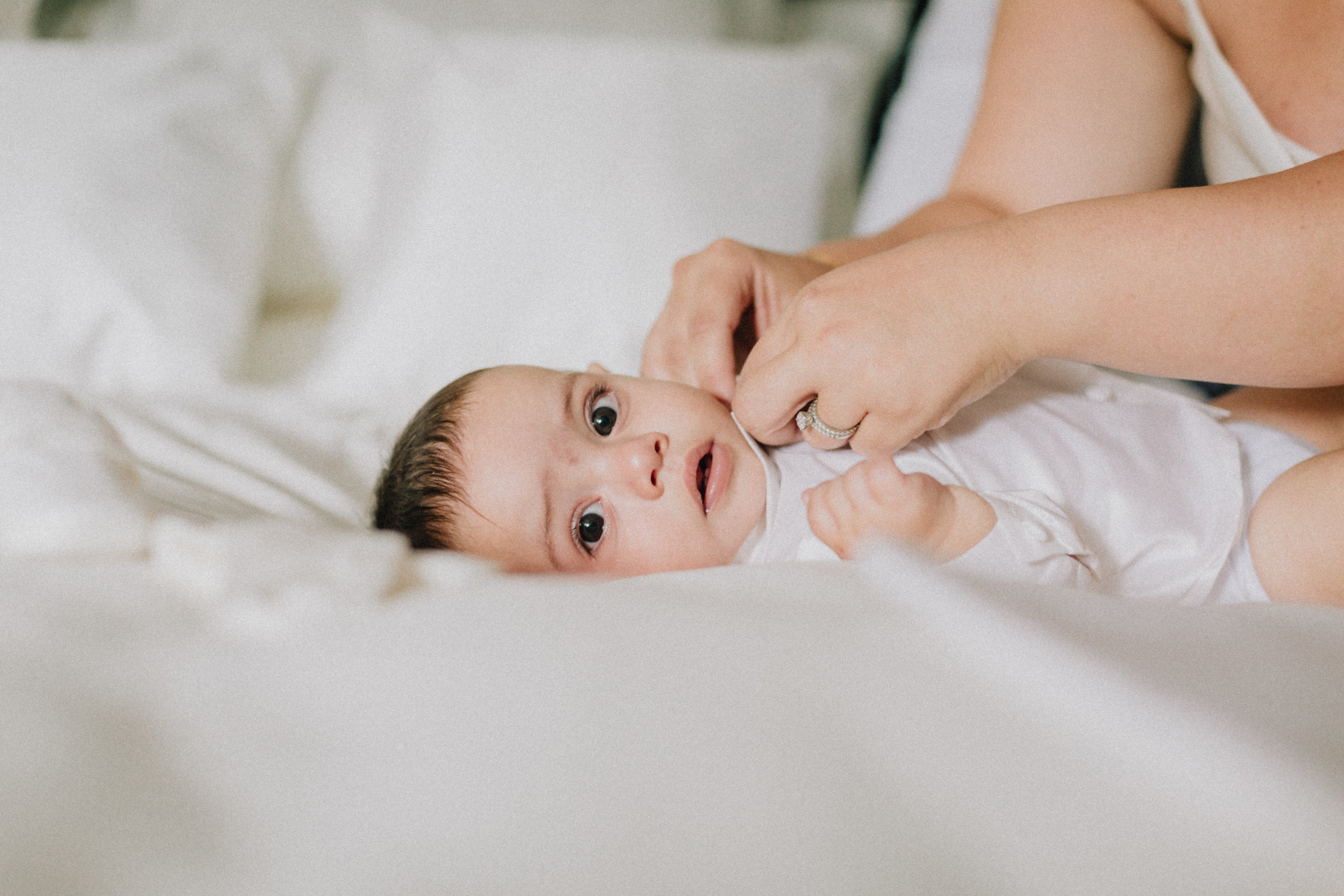 baby-lays-on-white-duvet-looking-at-the-camera.jpg